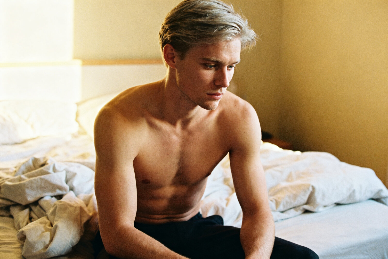 A fit young man waking up rested in warm morning light