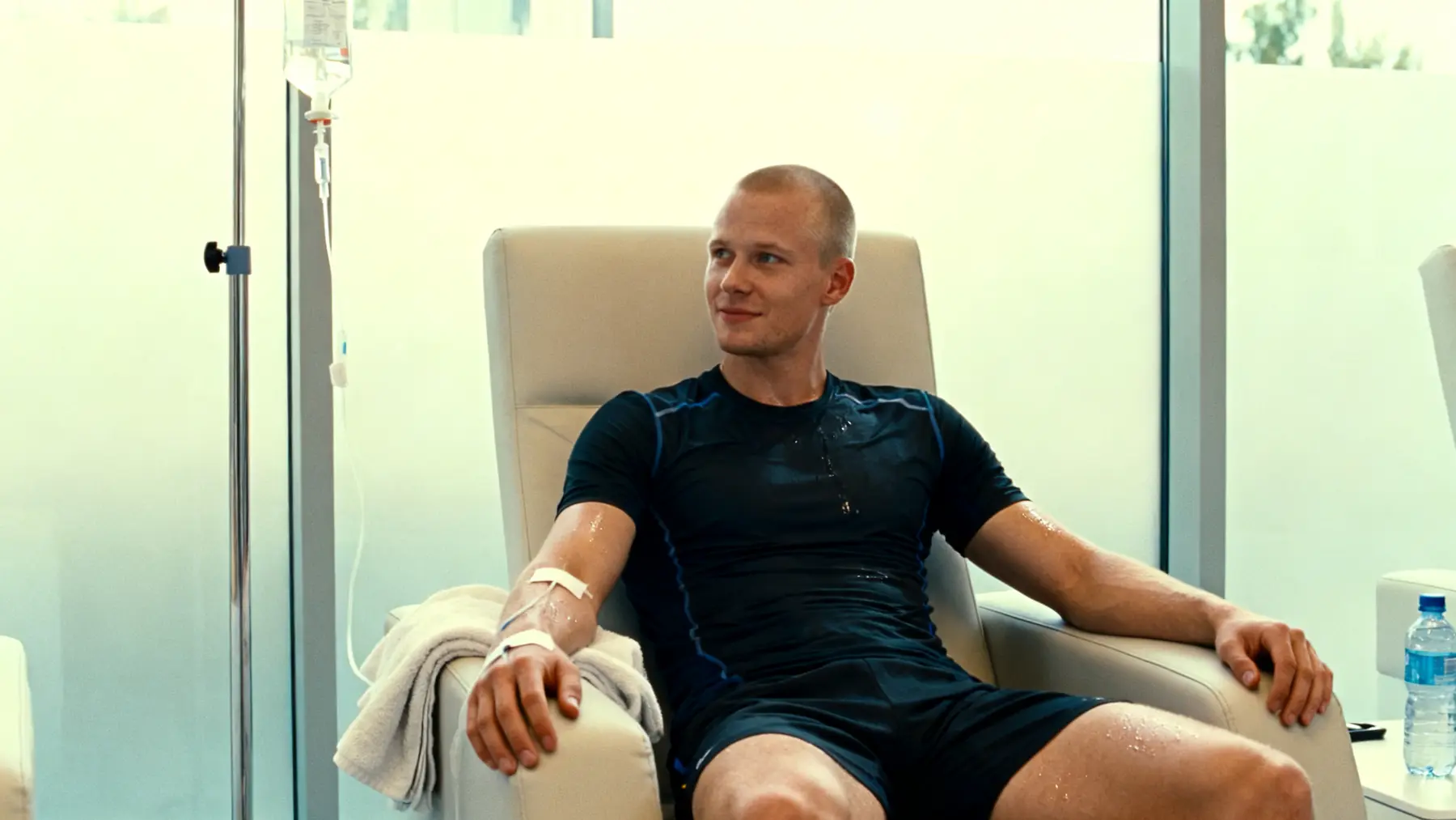 Athletic man in activewear relaxing in a recliner with an IV drip in a clinic