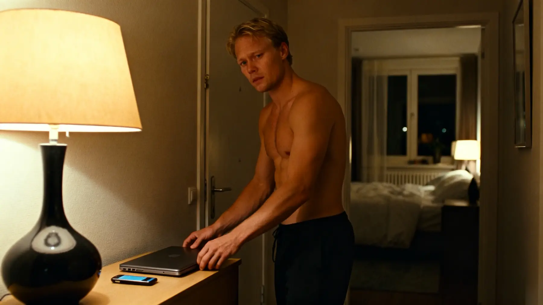 Young man leaving laptop and phone outside the bedroom at night