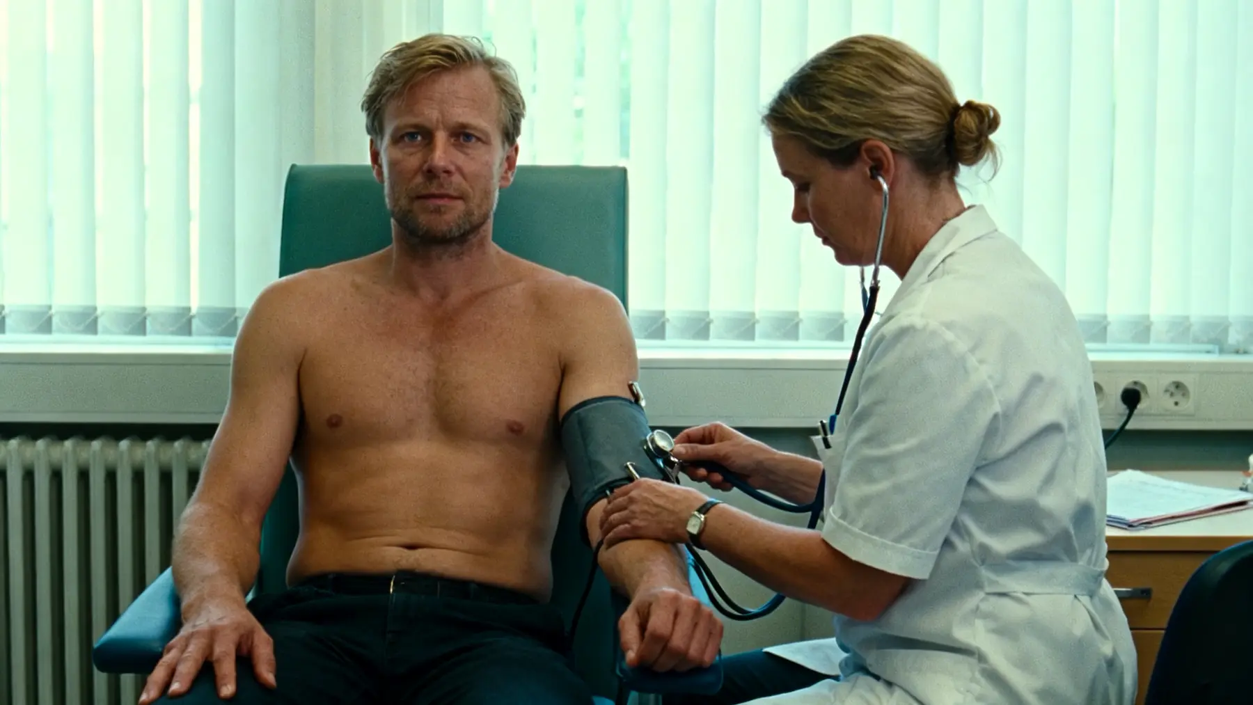 Doctor checking blood pressure on a fit man during cardiovascular visit