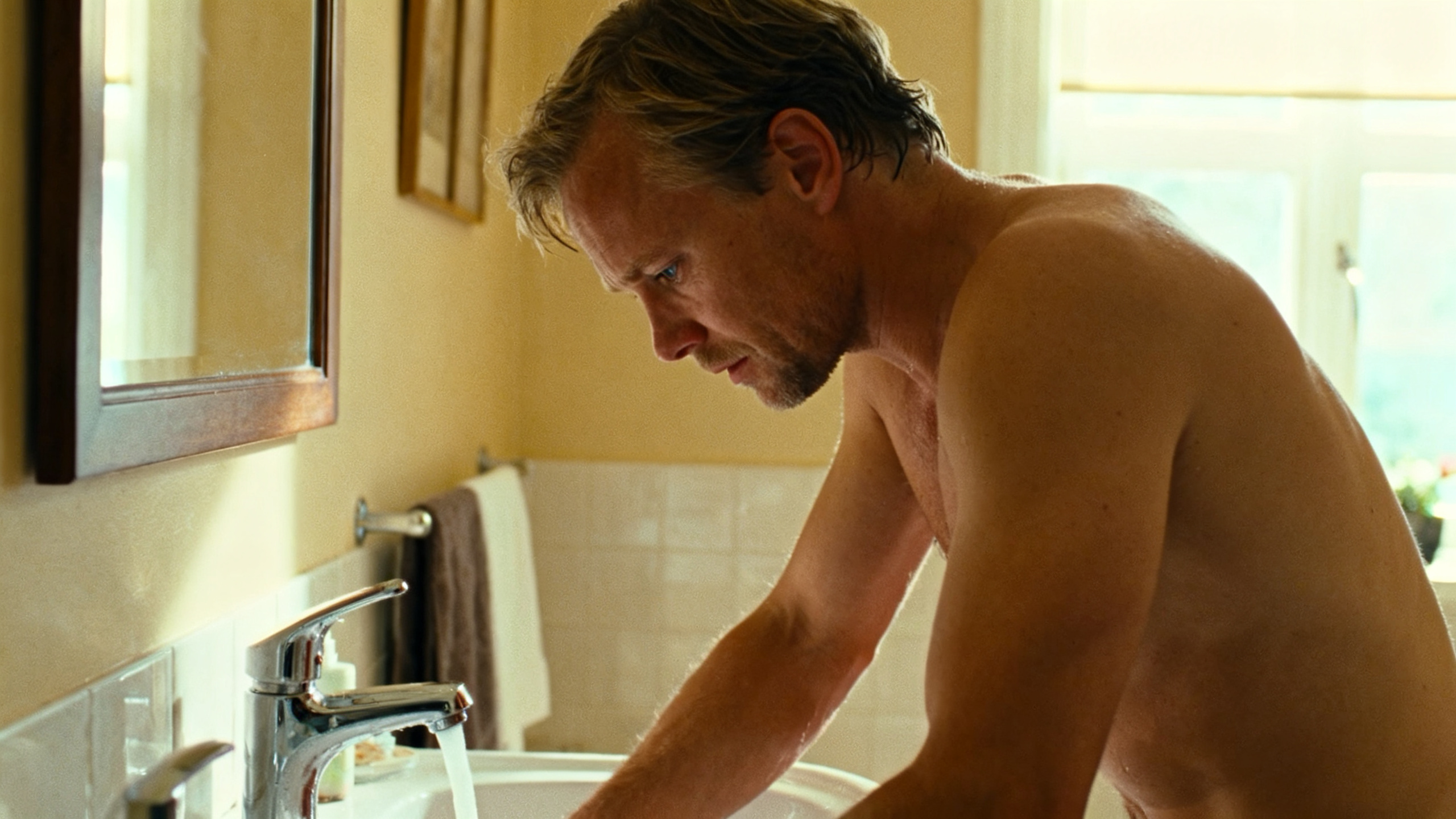 Young man at bathroom sink thinking about morning erections and health