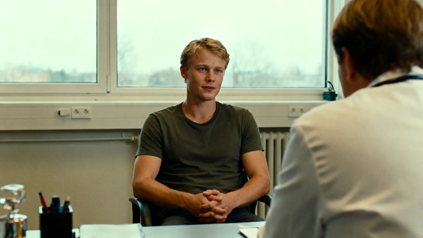 Young man discussing psychedelic research with a clinician in a plain office