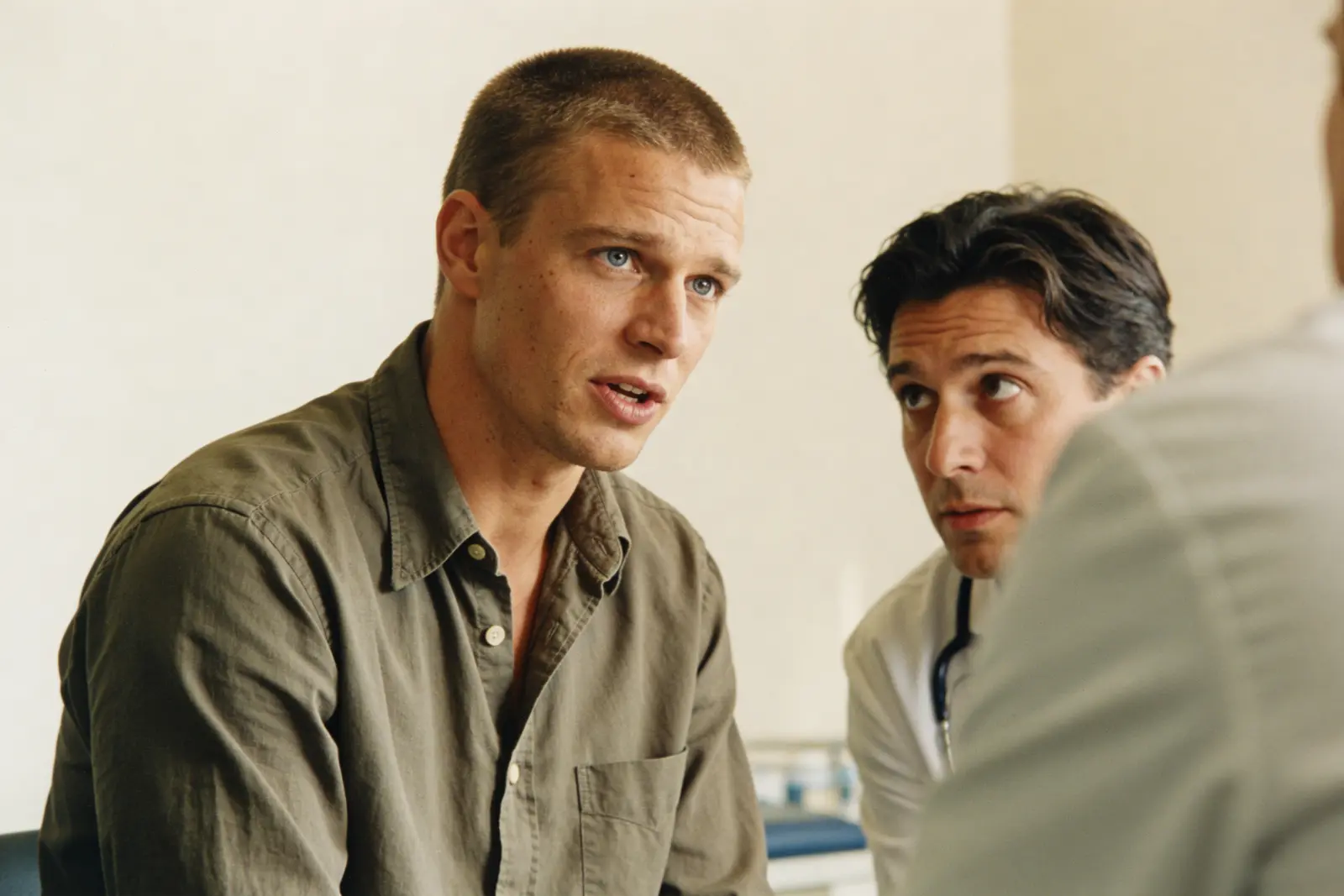 Two men talking intently across a table in a bright consultation room