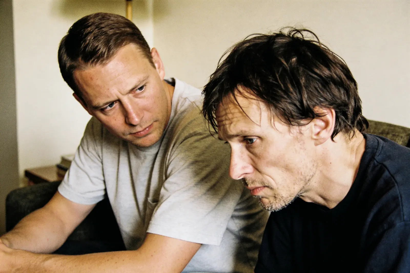 Two men sitting close, one looking concerned at a distressed friend