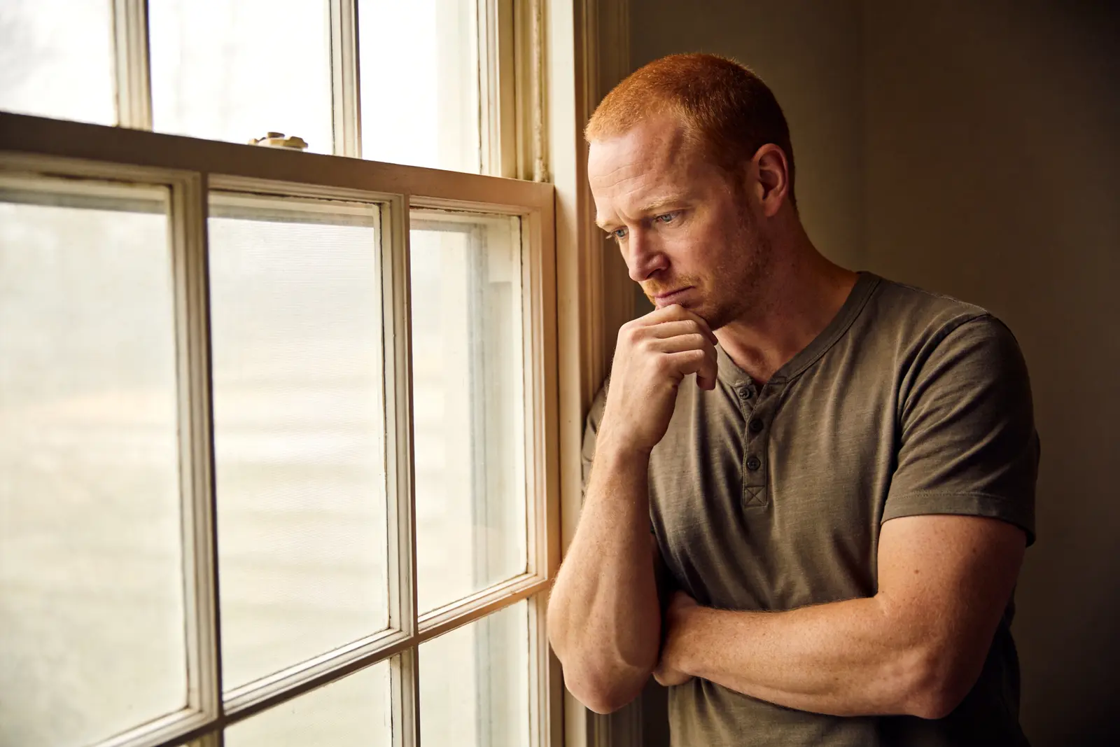 Man pausing thoughtfully at a window, considering his next move