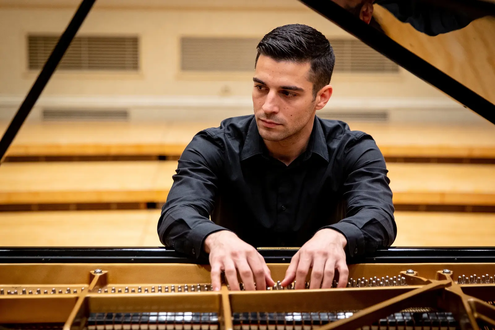 Pianist's steady hands resting on the keys in a quiet recital-hall moment before playing