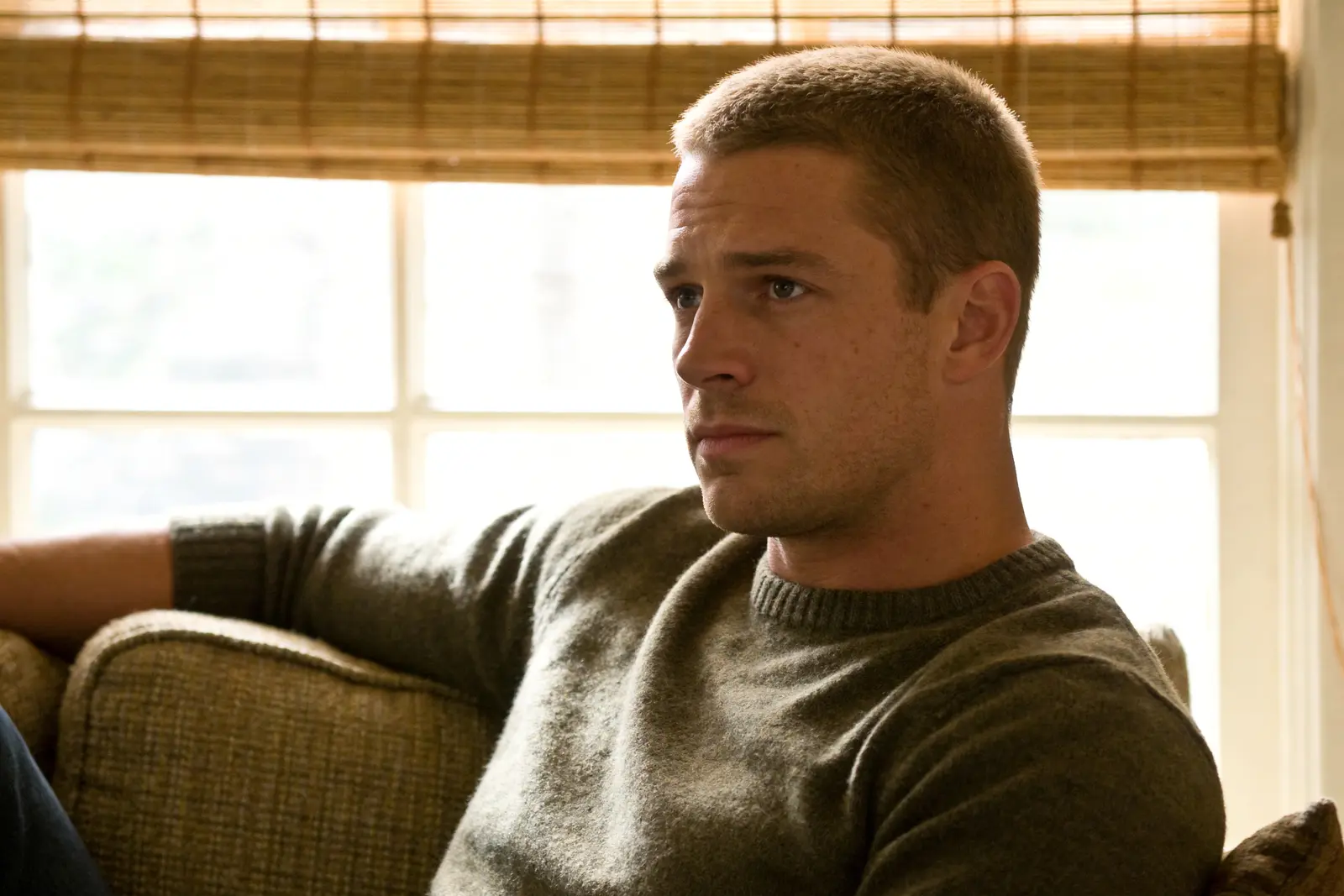 Calmer man at home, visibly less keyed-up, sitting relaxed on a couch