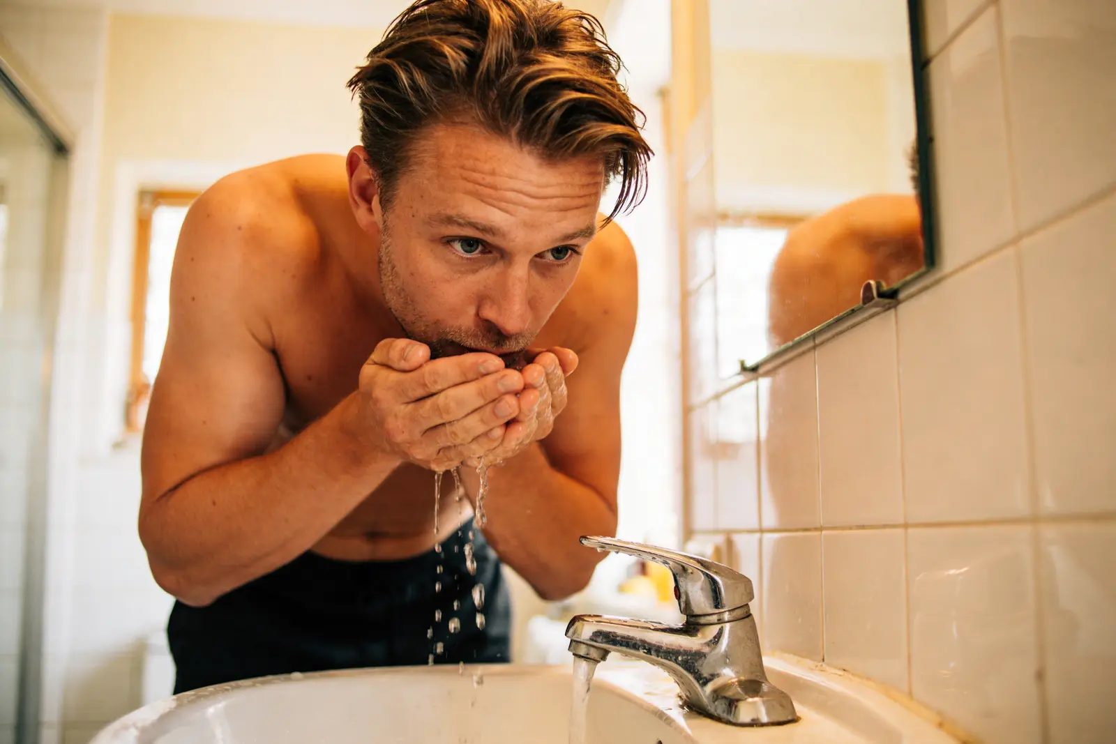 Man at the bathroom sink in the morning rinsing his mouth