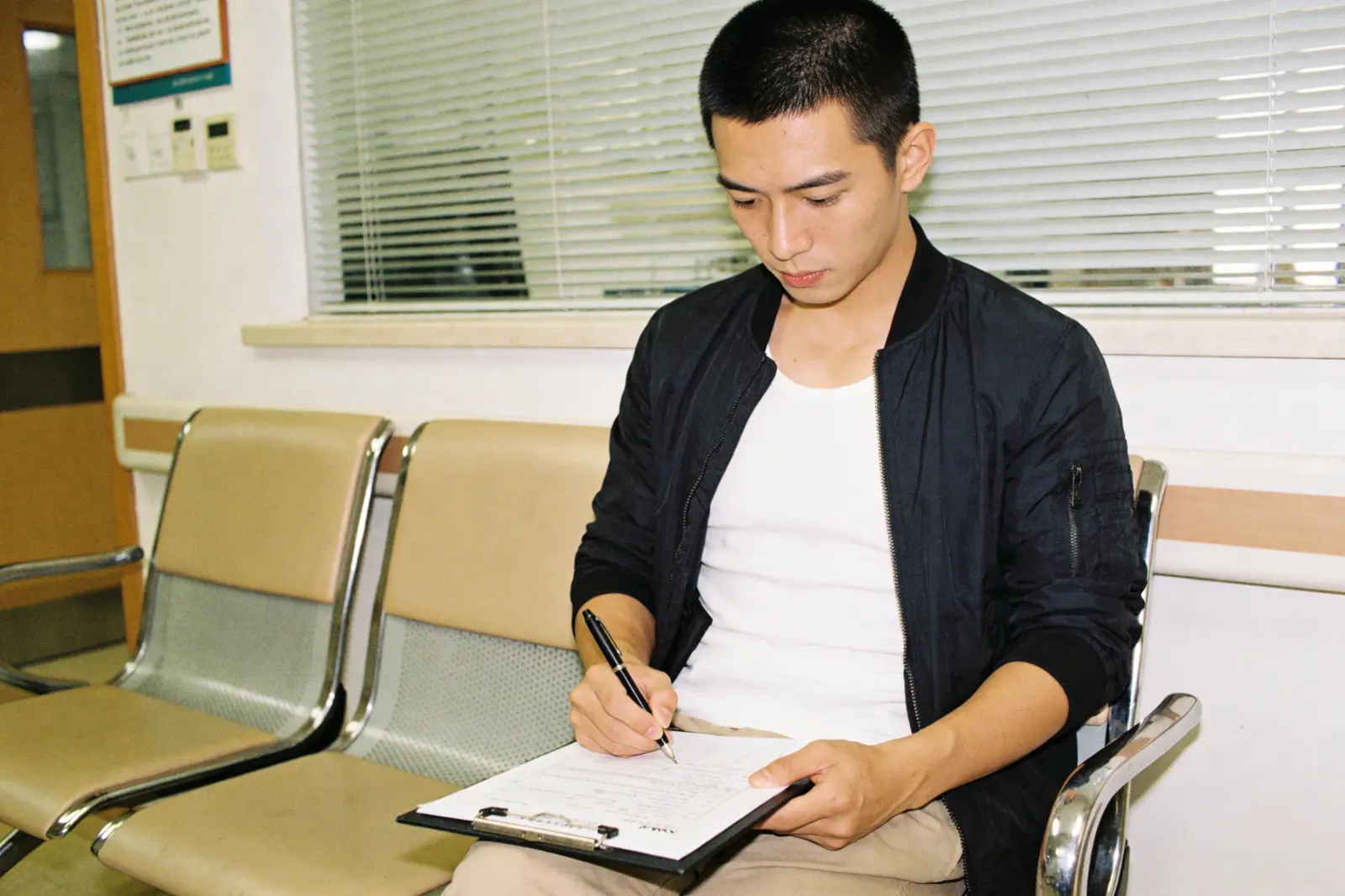 A man filling out a questionnaire on a clipboard in a waiting room