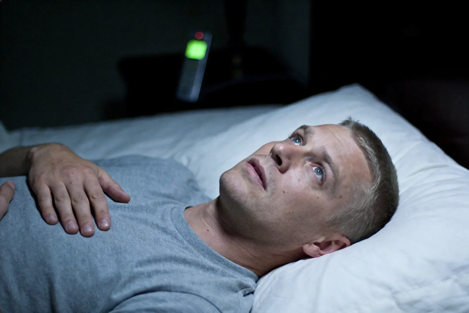 Man lying awake in bed at night, eyes open, unable to sleep