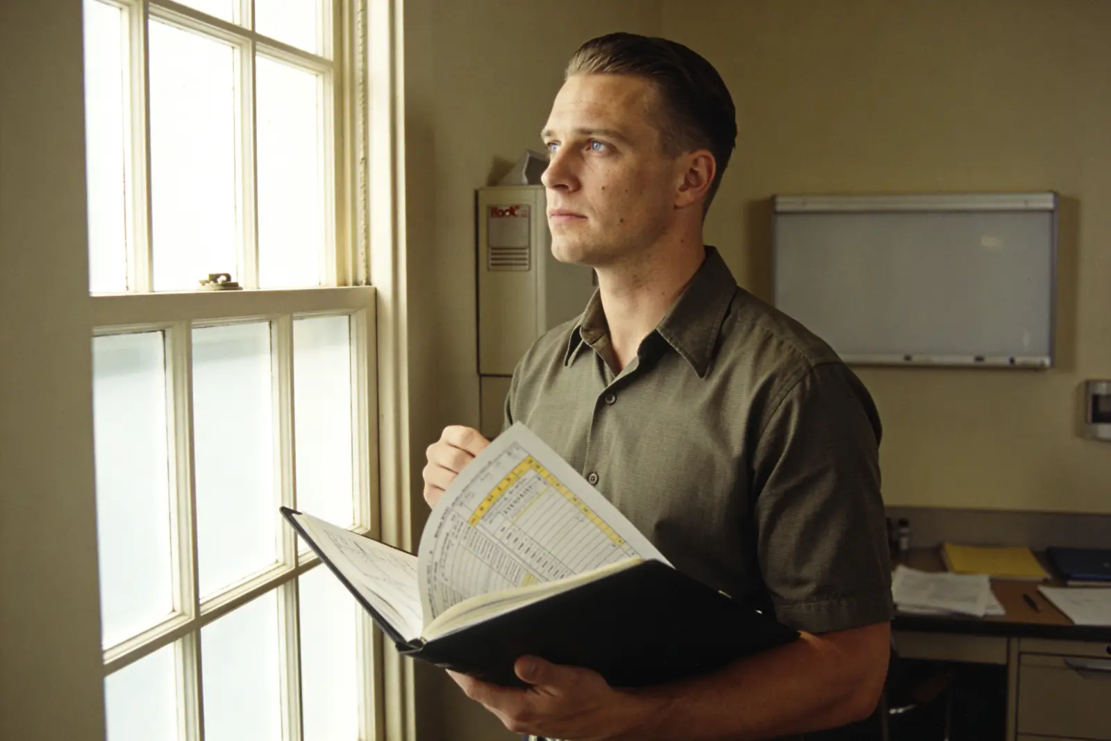 Clinician pausing thoughtfully at a window with a patient chart, deciding to slow the workup down