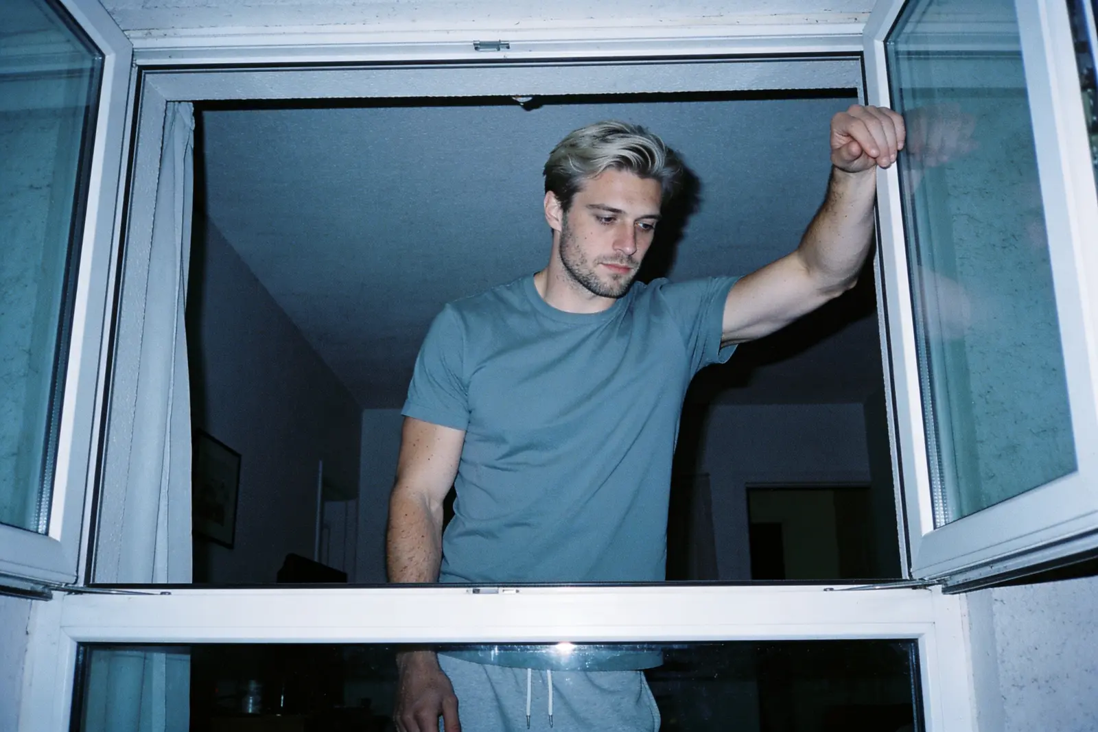 Man standing alone at a window before dawn after a sleepless restless high finally settles