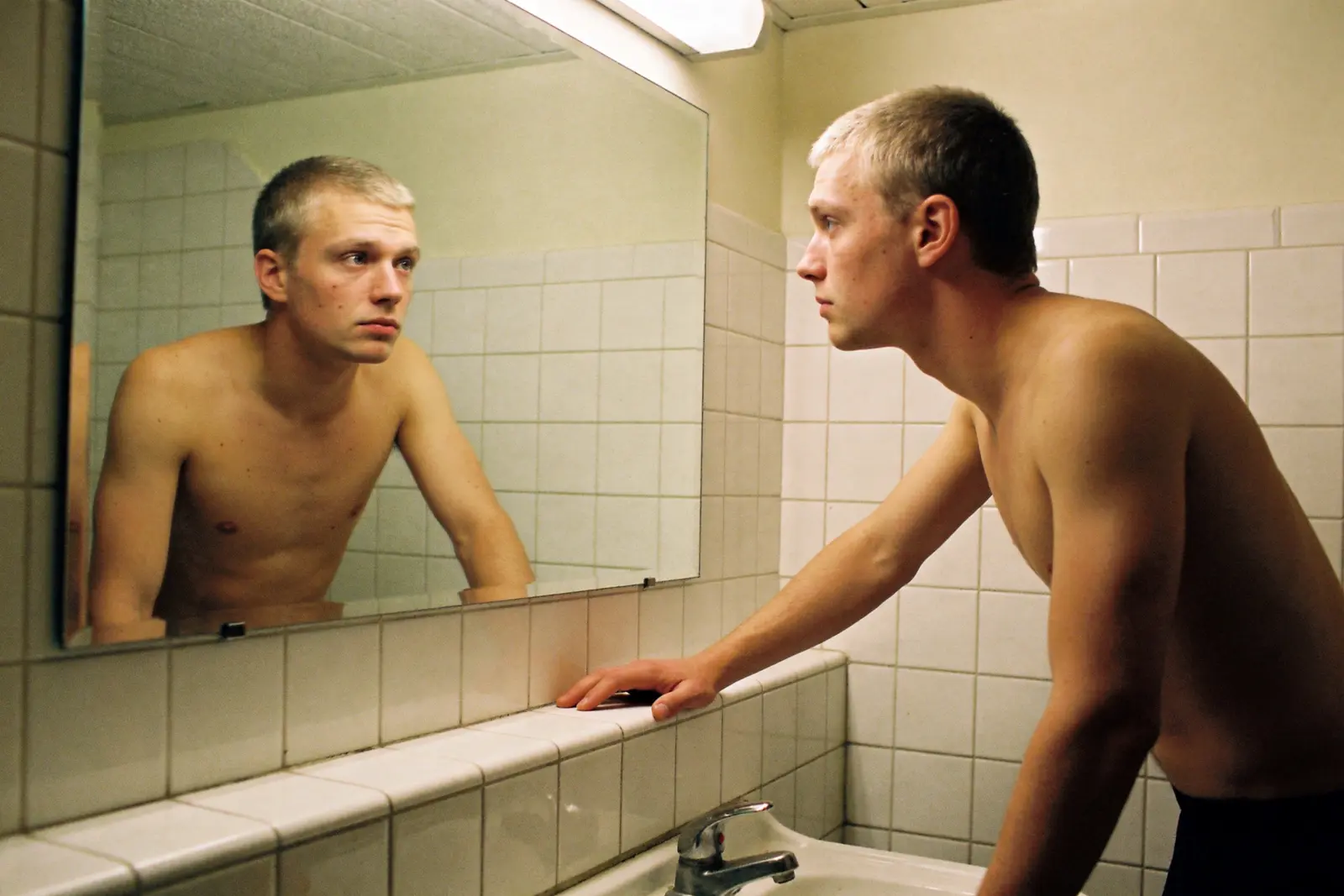 Man looking at himself in a bathroom mirror in the morning, thoughtful