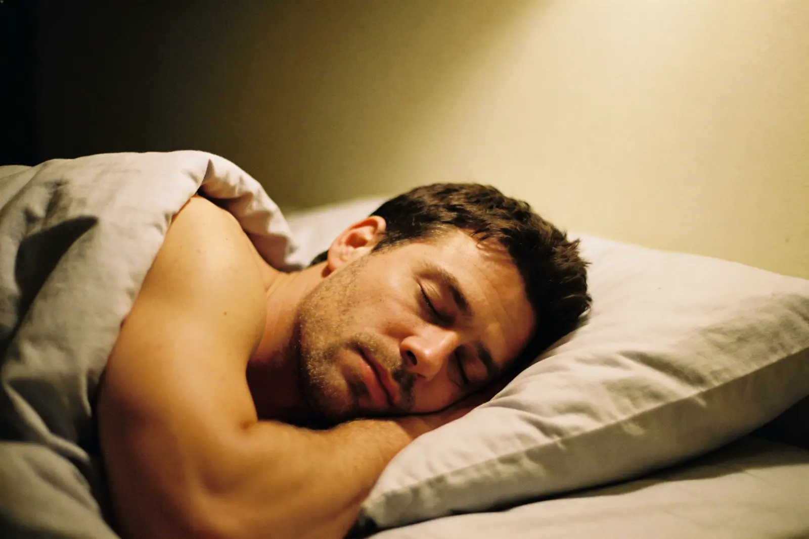 Man asleep on his side in a dim quiet bedroom