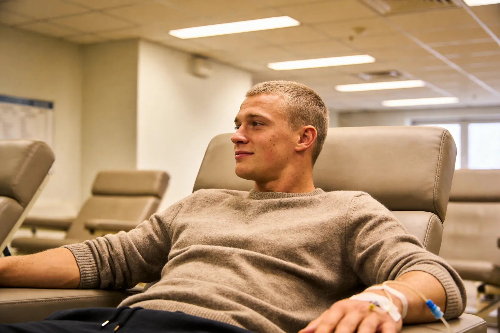 Man relaxed in a recliner with an IV drip in a softly lit wellness clinic