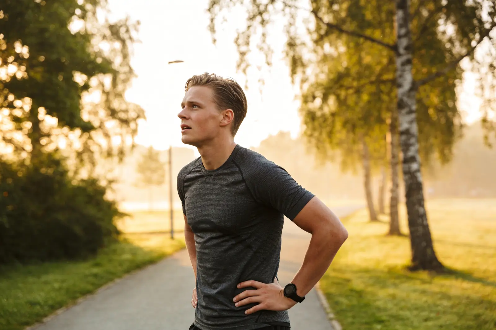 Fit man finishing a run outdoors at dawn, healthy and energized