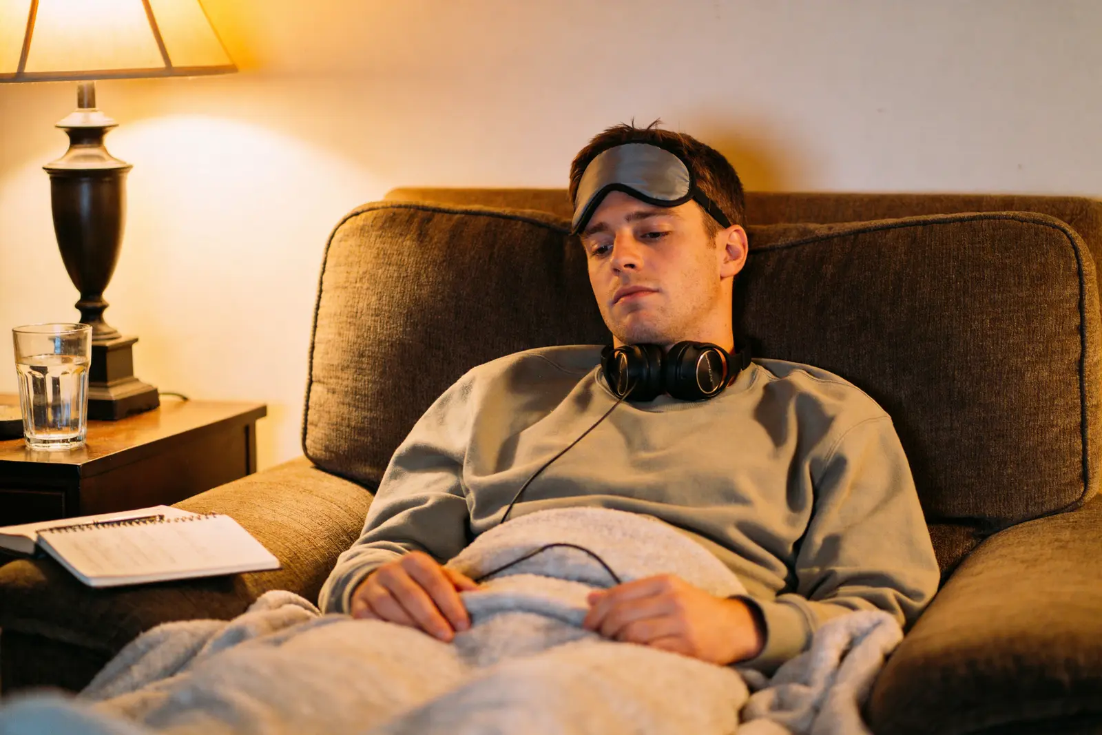A man settled on his couch at home with eye mask and headphones for a dosing session