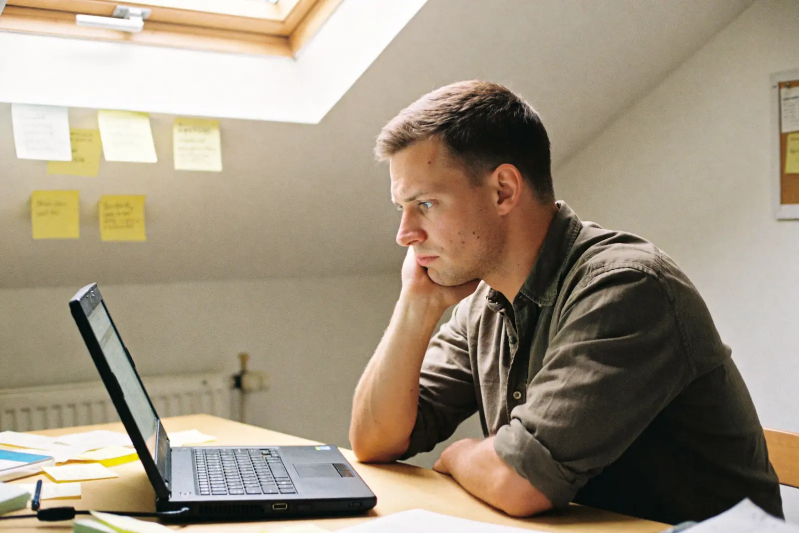 Man at a desk staring at his laptop, procrastinating, paralyzed by a small task