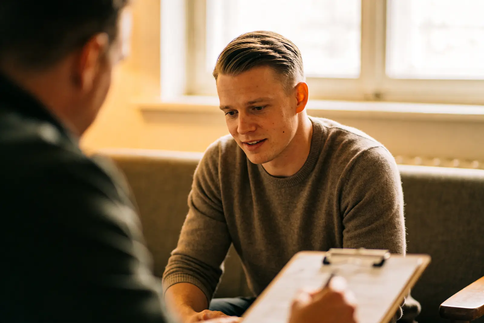 Man sitting on a couch in a therapy session, listening, a turning-point moment